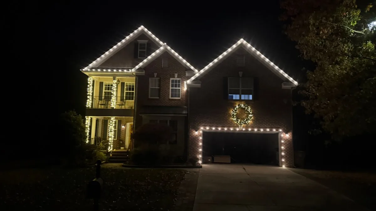 Brick two-story home with roofline lights, lit wreath and garage outline in Wake Forest, NC