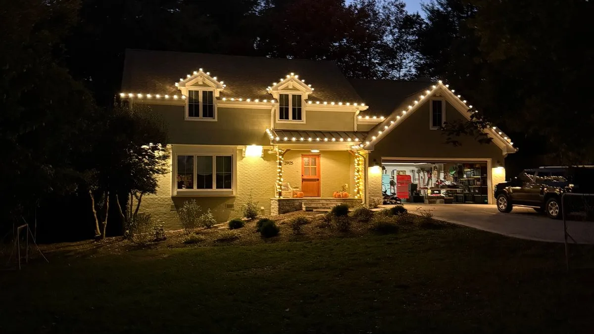 Christmas lights outlining the dormers and roofline of a cottage at dusk in Wake Forest, NC