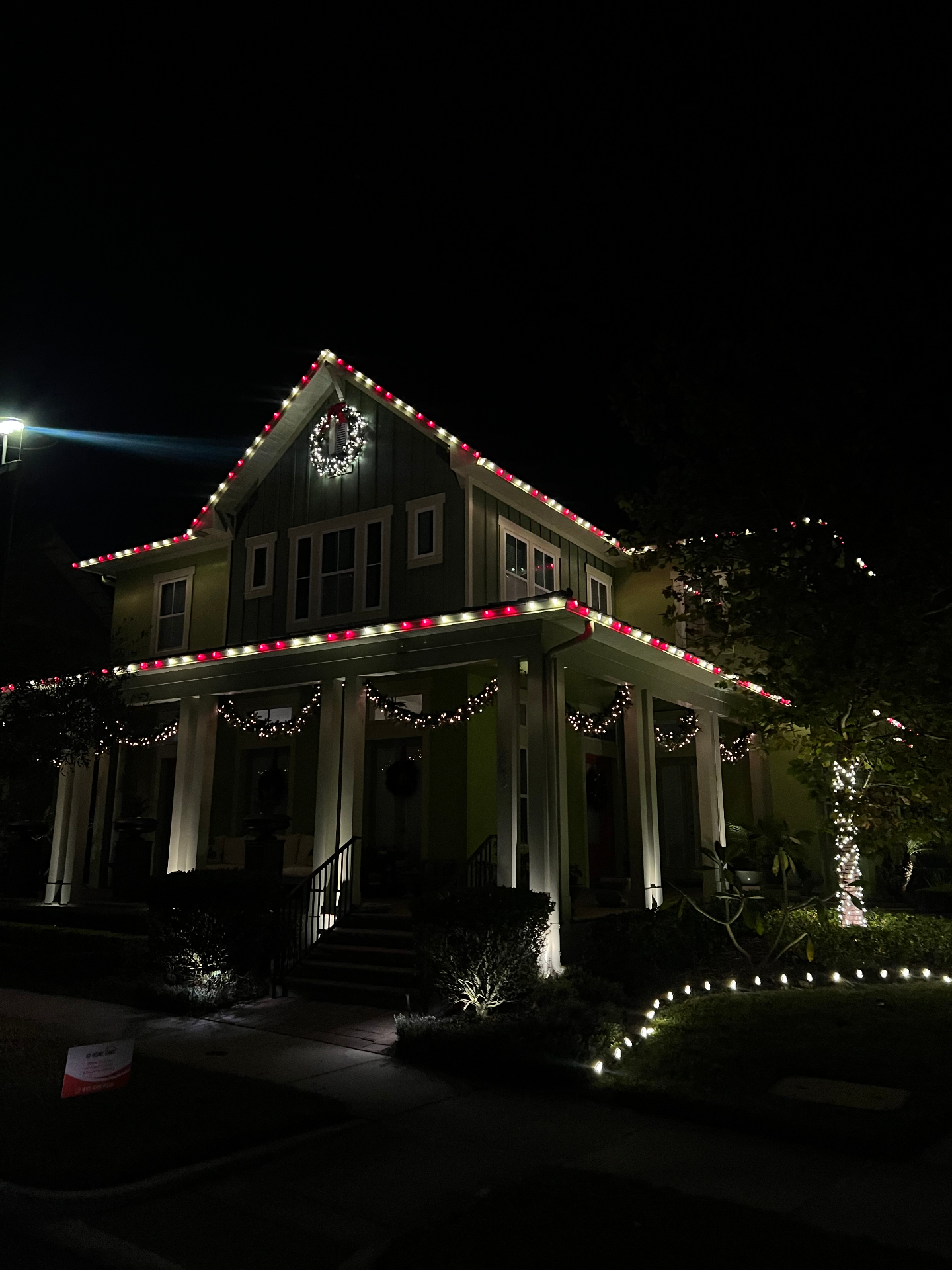 Victorian-style home with classic red and white holiday light installation